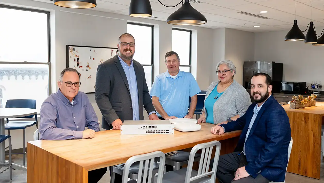 Wintek Business team members standing or seated around a table in an office