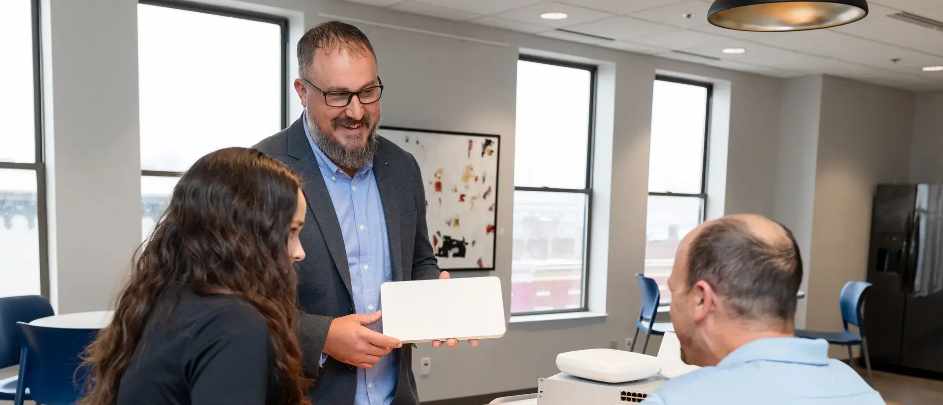 Three people at a table with networking hardware.